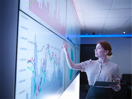Businesswoman studying graphs on screens Stock Photo - Premium Royalty-Free, Code: 649-08085249