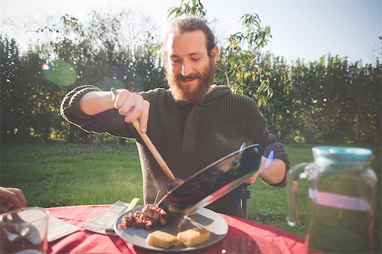 Young man holding frying pan serving food Stock Photo - Premium Royalty-Free, Image code: 649-08085369