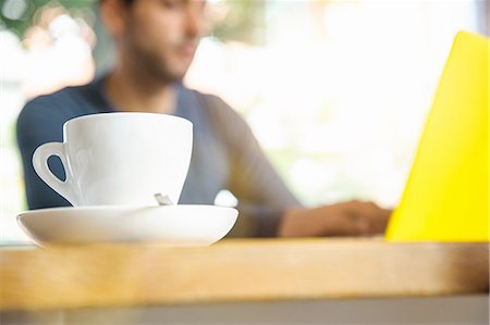 select focus - Young man using laptop in cafe, low angle view Stock Photo - Premium Royalty-Free, Code: 649-08085577