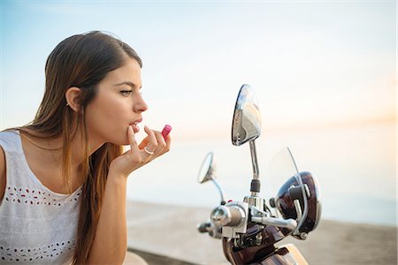 Young woman applying lipstick in motorcycle mirror, Manila, Philippines Stock Photo - Premium Royalty-Free, Code: 649-08085687
