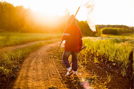 russia - Rear view of boy with butterfly net walking along dirt track at sunset, Sarsy village, Sverdlovsk Region, Russia Stock Photo - Premium Royalty-Free, Code: 649-08085810