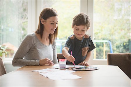 simsearch:614-06896990,k - Boy smiling with mother as he paints on paper at table in living room Stock Photo - Premium Royalty-Free, Code: 649-08085988