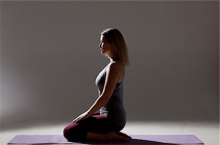 simsearch:400-08189778,k - Silhouetted low key shot of young woman kneeling on mat practicing yoga Foto de stock - Sin royalties Premium, Código: 649-08086055