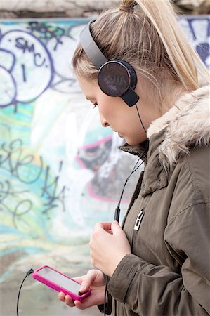 simsearch:649-08118826,k - Young woman choosing music for headphones in skatepark Foto de stock - Sin royalties Premium, Código: 649-08086051