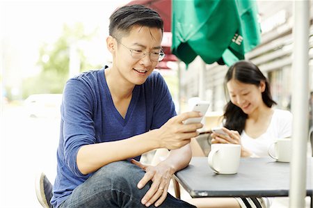 Tourist couple using smartphones at sidewalk cafe, The Bund, Shanghai, China Photographie de stock - Premium Libres de Droits, Code: 649-08086336