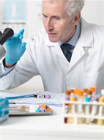 Doctor looking at patients blood slide under microscope with other samples for testing Stock Photo - Premium Royalty-Free, Code: 649-08086425