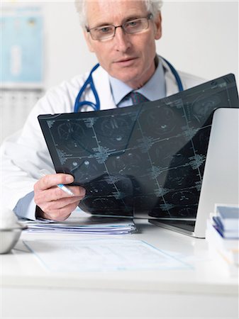 Doctor studying film sheet of computed tomography (CT) scans of various sections through the human head Stockbilder - Premium RF Lizenzfrei, Bildnummer: 649-08086433