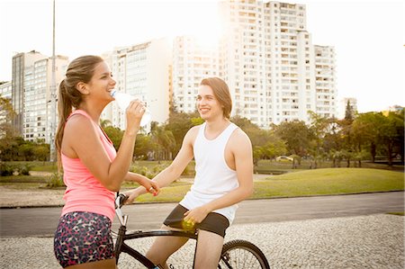 simsearch:649-08086344,k - Young couple chatting whilst preparing to cycle in park Foto de stock - Royalty Free Premium, Número: 649-08086443