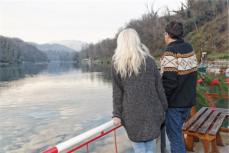 person leaning on rail with back - Heterosexual couple standing beside lake, Lombardy, Italy, rear view Stock Photo - Premium Royalty-Free, Code: 649-08086673