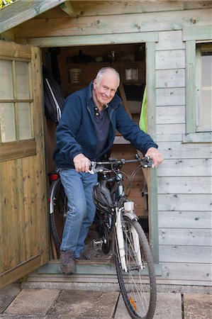 Senior man on bike by shed Foto de stock - Royalty Free Premium, Número: 649-08086708