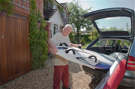 senior man eye contact one person - Senior man removing surfboard from car boot Stock Photo - Premium Royalty-Free, Code: 649-08086715