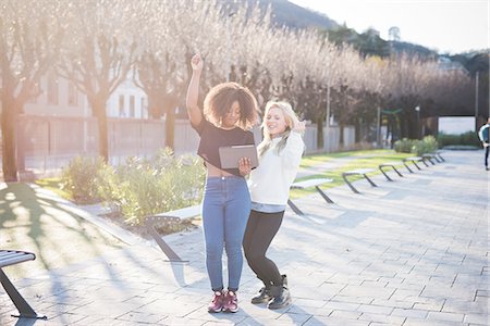 Two young female friends in park laughing at digital tablet, Como, Italy Stock Photo - Premium Royalty-Free, Code: 649-08086813