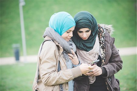 faith (not religious) - Two female friends in park reading text on smartphones Stock Photo - Premium Royalty-Free, Code: 649-08086866