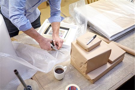 Man cutting bubble wrap on table in picture framers workshop Stock Photo - Premium Royalty-Free, Code: 649-08086944