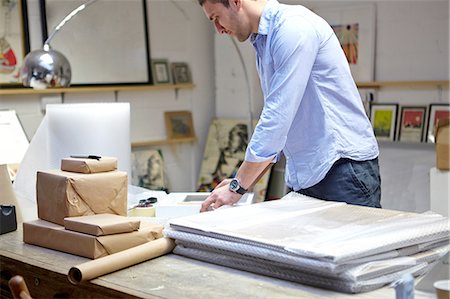 Man wrapping frames in bubble wrap on table in picture framers workshop Photographie de stock - Premium Libres de Droits, Code: 649-08086943