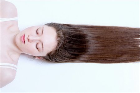 Young woman lying down, hair stretched out behind her Photographie de stock - Premium Libres de Droits, Code: 649-08117771