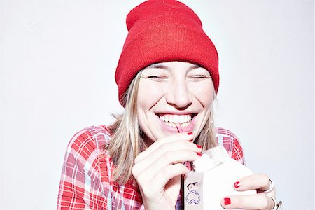 Close up studio portrait of young woman in red hat drinking juice Stock Photo - Premium Royalty-Free, Code: 649-08117847