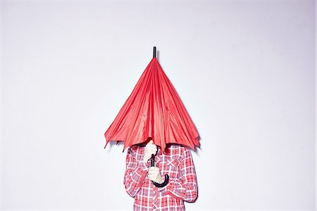 embarrassed woman - Studio shot of young woman holding red umbrella over her head Stock Photo - Premium Royalty-Free, Code: 649-08117848