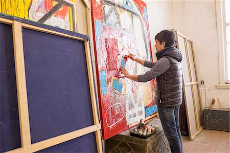 Artist drawing on abstract painting in studio Stock Photo - Premium Royalty-Free, Code: 649-08117865