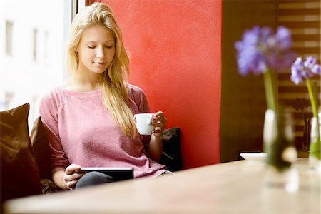drinking coffee in a cafe - Young woman in cafe window seat drinking coffee and using digital tablet Stock Photo - Premium Royalty-Free, Code: 649-08117912