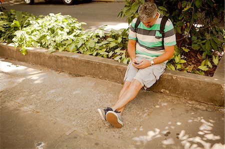 simsearch:649-07560148,k - Mature man sitting on sidewalk texting on smartphone, Rio De Janeiro, Brazil Photographie de stock - Premium Libres de Droits, Code: 649-08117938