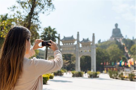 simsearch:649-07238586,k - Young female tourist taking smartphone photographs of Tian Tan Buddha, Po Lin Monastery, Lantau Island, Hong Kong, China Foto de stock - Sin royalties Premium, Código: 649-08117931