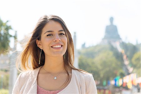 Portrait of young female tourist in front of Tian Tan Buddha, Po Lin Monastery, Lantau Island, Hong Kong, China Stock Photo - Premium Royalty-Free, Code: 649-08117933