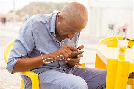 Mature man concentrating on smartphone at bar on Ipanema beach, Rio De Janeiro, Brazil Stock Photo - Premium Royalty-Free, Code: 649-08118049