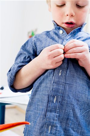 Boy buttoning shirt at home Photographie de stock - Premium Libres de Droits, Code: 649-08118141