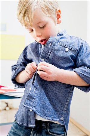 shirt - Boy buttoning shirt at home Photographie de stock - Premium Libres de Droits, Code: 649-08118142