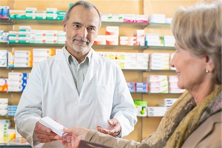 pharmacy shelf - Pharmacist handing medicine to senior woman in pharmacy Stock Photo - Premium Royalty-Free, Code: 649-08118518