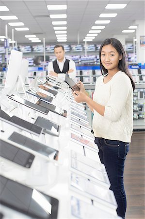 Portrait of young female shopper browsing digital tablets in electronics store Stock Photo - Premium Royalty-Free, Code: 649-08118534