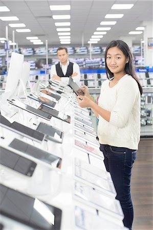 shopping japanese - Portrait of young female shopper browsing digital tablets in electronics store Stock Photo - Premium Royalty-Free, Code: 649-08118534