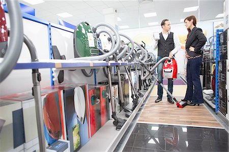 purchase - Shop assistant demonstrating vacuum cleaner in electronics store Stock Photo - Premium Royalty-Free, Code: 649-08118532