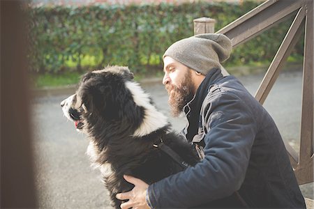 simsearch:649-08118581,k - Mid adult man sitting with dog, outdoors Photographie de stock - Premium Libres de Droits, Code: 649-08118572