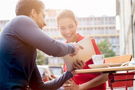 Young man and woman sitting outside cafe, looking at digital tablet Stock Photo - Premium Royalty-Free, Code: 649-08118639