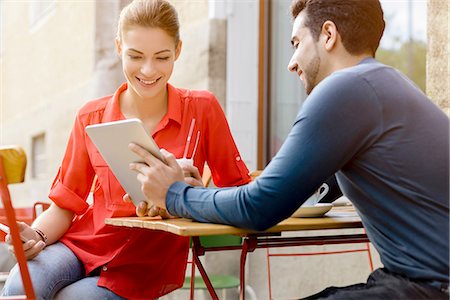 people sitting in meetings - Young man and woman sitting outside cafe, looking at digital tablet Stock Photo - Premium Royalty-Free, Code: 649-08118640