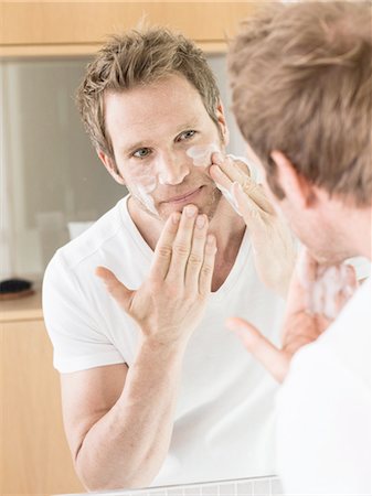 Man looking in bathroom mirror applying face cream Photographie de stock - Premium Libres de Droits, Code: 649-08118750