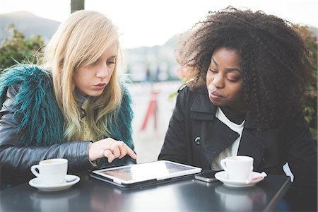 simsearch:649-08840347,k - Two young women using touchscreen on digital tablet at sidewalk cafe, Lake Como, Como, Italy Stock Photo - Premium Royalty-Free, Code: 649-08118799