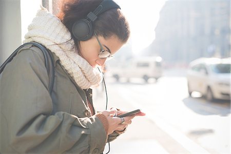 simsearch:649-08118826,k - Young woman wearing headphones choosing smartphone music on street Foto de stock - Sin royalties Premium, Código: 649-08118805