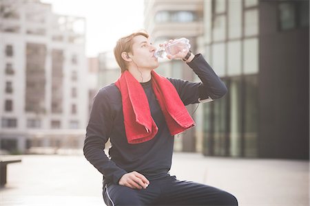 Young male runner drinking water on bench in city square Stock Photo - Premium Royalty-Free, Code: 649-08118845