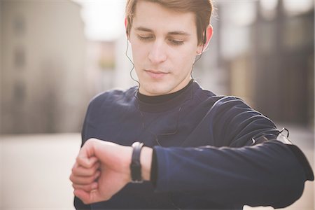 running and headphones - Young male runner checking wristwatch in city square Stock Photo - Premium Royalty-Free, Code: 649-08118840