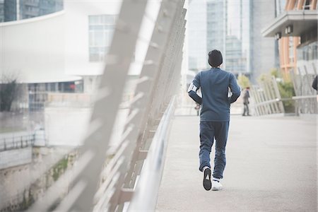 Rear view of young male runner on city footbridge Stock Photo - Premium Royalty-Free, Code: 649-08118853