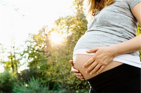 simsearch:649-07437409,k - Pregnant woman holding belly, outdoors, mid section Stock Photo - Premium Royalty-Free, Code: 649-08118903