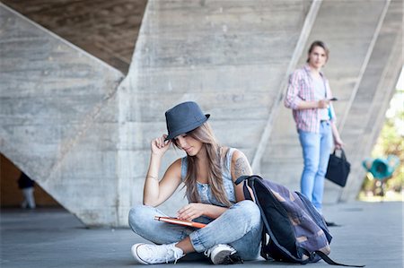 Female student sitting on floor with book, man watching Photographie de stock - Premium Libres de Droits, Code: 649-08118931