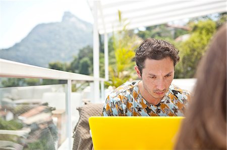 family in balcony - Mid adult man sitting on balcony, using laptop Stock Photo - Premium Royalty-Free, Code: 649-08119010