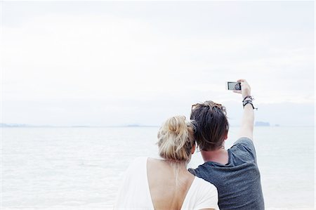 Rear view of young couple taking smartphone selfie on beach, Kradan, Thailand Stock Photo - Premium Royalty-Free, Code: 649-08119330