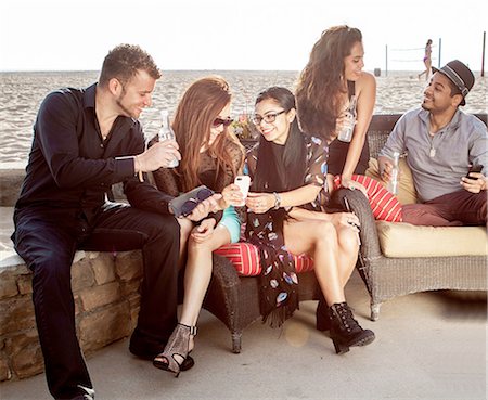 Group of friends at a beach bar talking and looking at smart phone Foto de stock - Sin royalties Premium, Código: 649-08119406