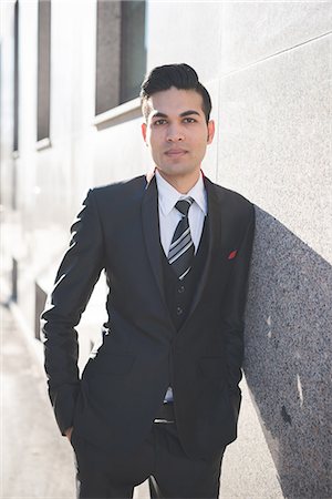 Young businessman leaning against wall Stock Photo - Premium Royalty-Free, Code: 649-08125103