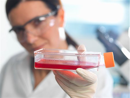 Female cell biologist holding flask containing stem cells, cultivated in red growth medium Stock Photo - Premium Royalty-Free, Code: 649-08125181